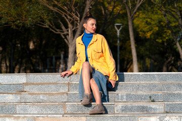 Poster - A young woman sits on the steps on the street.