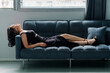 Young beautiful brunette girl in a black dress sitting on the sofa