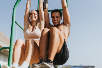 Caucasian couple does pull ups on metal bars in park. Enjoying fresh air fitness, they exercise outdoors, motivated and persistent in their workout routine. Healthy lifestyle, positive results.