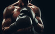Male boxer wears boxing gloves and practices fighting hard sweating all over Powerful black background