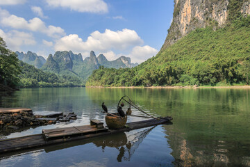 landscape of karsten mountain along the li river in guilin with a bamboo raft and two comorants perc