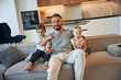 © standret - Father with two baby boys is sitting at sofa
