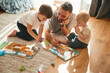 © standret - Lying down, board game. Father is playing with two little boys on the floor with toys