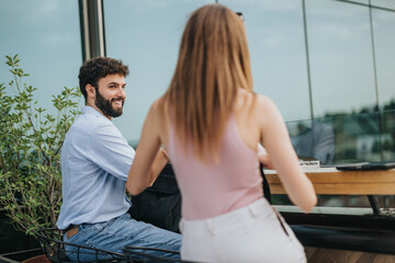 A business couple discusses growth strategies in an urban cafe on a cloudy day. They exchange ideas for market expansion and profit growth, showcasing their successful teamwork as young investors.