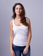 Wall Mural - Portrait, fashion and confident with a young woman in studio on a gray background looking happy. Smile, style and clothes with a trendy female model in a casual denim jeans and tank top outfit