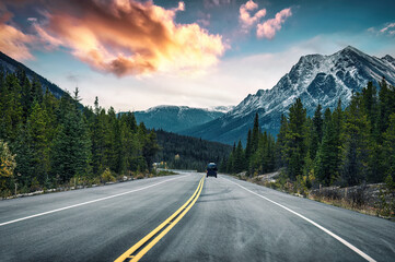 Wall Mural - Road trip with van driving on the road in rocky mountains and pine forest at national park