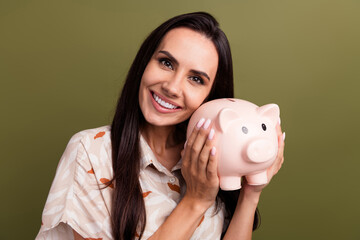 Sticker - Photo of optimistic toothy beaming smile gorgeous lady hugs her small toy piggy bank accumulates money isolated on khaki color background