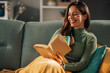 © Zamrznuti tonovi - Happy woman relaxing on a couch at home and reading a book.
