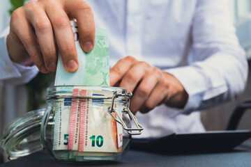 Man hands counting expenses banknotes of euro cash from glass jar in the piggy bank on calculator. Close up of hands unrecognizable Businessman. Save up budget investment concept. Euros fund savings