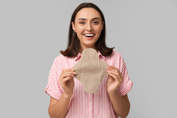 Sticker - Beautiful young woman with reusable menstrual pad on grey background