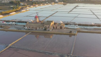 Wall Mural - Windmill at sunset, Riserva Naturale Isole dello Stagnone di Marsala, salt flats in the evoporation pond, Trapani province, Sicily, Italy, Europe. Aerial view