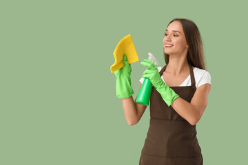 Wall Mural - Pretty young woman with rag and bottle of detergent on green background