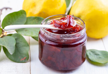 Wall Mural - Homemade quince jam in a glass jar on an old wooden background. Fresh quince fruits and leaves and quince jam. (Turkish name; ayva receli)