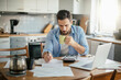 © Geber86 - Serious young man reading bill document at home