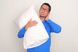 © KrishnaTedjo - Adult Asian man suffering back neck pain while holding a sleeping pillow