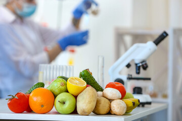 Wall Mural - fresh vegetables, fruits on table and scientist proceeding quality control in laboratory