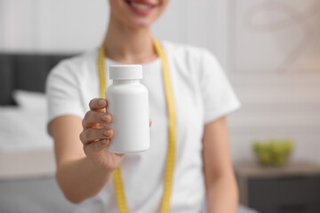 Sticker - Woman holding bottle of pills in room, closeup. Weight loss