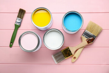 Poster - Cans of colorful paints with brushes on pink wooden table, flat lay