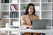 © Kainnika - Attractive asian businesswoman secretary working with laptop and paperwork in office.