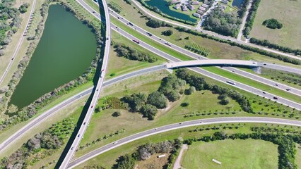 Wall Mural - Aerial view of freeway overpass junction with fast moving traffic cars and trucks in american rural area. Interstate transportation infrastructure in USA