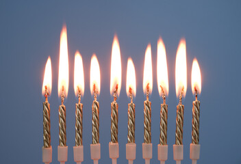 Ten golden birthday candles burning on blue background.