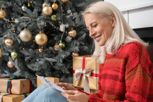 Mature Woman With Greeting Card For Christmas Celebration At Home