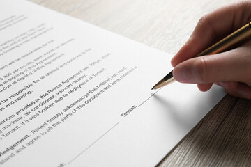 Canvas Print - Woman signing document with pen at wooden table, closeup