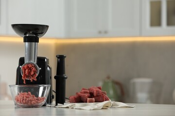 Sticker - Electric meat grinder with beef mince on white table in kitchen, space for text