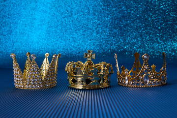 Poster - Epiphany Day or Dia de Reyes Magos concept. Three gold crowns on blue sparkling background