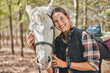 Portrait of happy woman with horse standing in trees, embrace and love for animals, pets or dressage in forest. Equestrian sport, girl jockey or rider in woods for adventure, pride and smile on face.