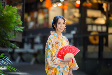 Sticker - Asian woman try to wear Japanese kimono with the traditional Japanese village background