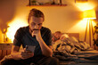 disloyal bearded gay man browsing internet on smartphone near partner sleeping at night in bedroom