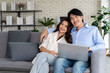 © pixs4u - Young couple planning future together on couch with Laptop internet