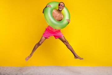 Wall Mural - Full length photo of funky excited masculine guy jumping high having fun enjoying vacation isolated yellow color background