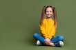 Full length photo of lovely kid dressed yellow sweatshirt denim pants sit near offer empty space isolated on khaki color background