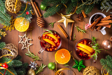 Wall Mural - Traditional Christmas aromatic mulled wine cocktail, red wine grog tea drink with spices, cinnamon, orange and rosemary sprig, on Christmas New Year decorated wooden cozy background