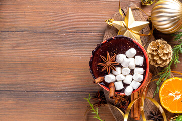 Wall Mural - Winter aromatic hot chocolate cup with Christmas background. Mug of dark hot cocoa drink with cinnamon, anise, spices and marshmallow, on cozy Christmas and New Year holiday decorated background 