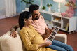 Happy Indian Pregnant women or wife with caring husband checking ultrasound scan reports at home - concept of Parenthood journey, bonding and Expectant parents