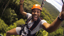 Young Man Engaged In A Thrilling Ziplining Adventure Through A Dense Rainforest Canopy. He Soars Above The Treetops, He Laughter And Excitement Echoing Through The Jungle.