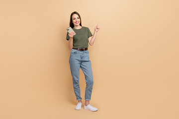 Canvas Print - Full body photo of lady wear khaki t shirt point finger mockup website with useful links using cellphone isolated on beige color background