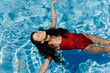 © SHOTPRIME STUDIO - Happy woman swimming in the pool in red swimsuit with loose long hair relaxed in the sunshine, skin protection with sunscreen, concept of relaxing on vacation in tropical climate, lifestyle.