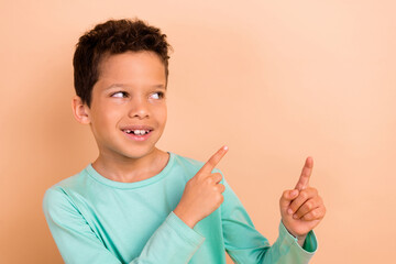 Photo of cheerful nice cute brown hair boy wear stylish turquoise clothes two hands direct empty space isolated on beige color background