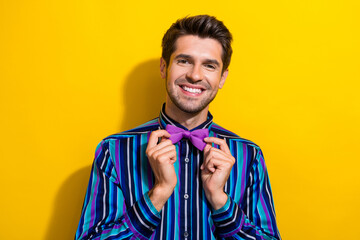 Poster - Portrait of pleasant cheerful gentleman dressed stylish shirt touching bow tie smiling isolated on vibrant yellow color background