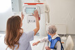 © Yakobchuk Olena - Back view of the nurse woman preparing to scanning woman patient hand on modern X-ray