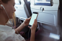 Woman Sitting On Airplane Using Smartphone With Empty Blank White Screen Mockup