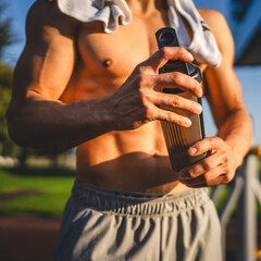 Wall Mural - One caucasian man young male athlete take a brake during outdoor training in the park outdoor gym hold supplement shaker in hand happy confident strong copy space