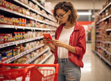 Fototapeta  - young woman buying diary product and reading food label in grocery store