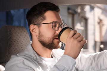 Wall Mural - To-go drink. Handsome man drinking coffee in car