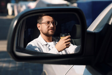 Canvas Print - Coffee to go. Handsome man with paper cup of drink, view through car side mirror