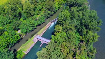 Wall Mural - Aerial view of a mountain freshwater river surrounded by green trees at a hydroelectric power station. Green energy on the planet. Ecology. The rocky bottom of the river. drone video. Trezzo sull'Adda